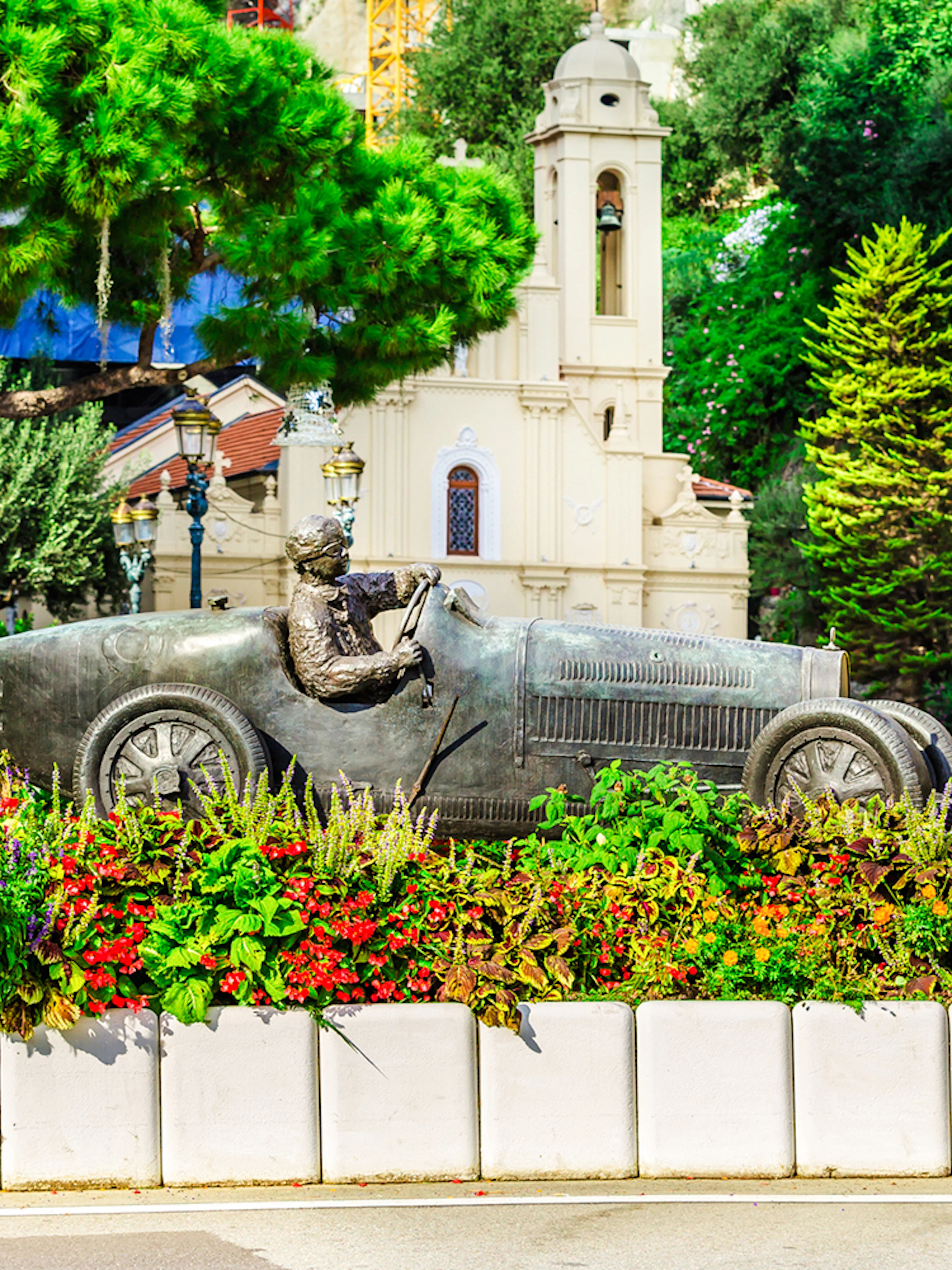 Bronze race car statue surrounded by flowers on Monaco Formula 1 Walking Tour.