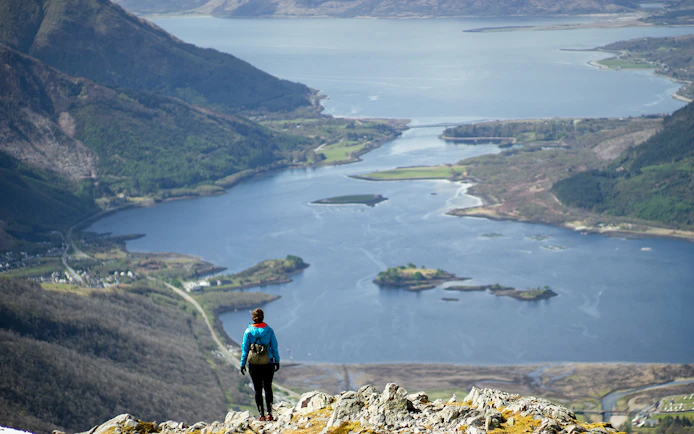 Person overlooking a scenic view of a loch and hills on the St Andrews & Fife tour from Edinburgh.