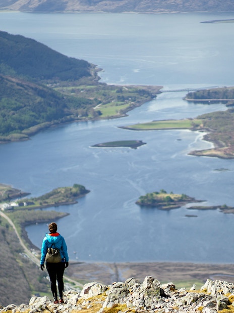 Person overlooking a scenic view of a loch and hills on the St Andrews & Fife tour from Edinburgh.