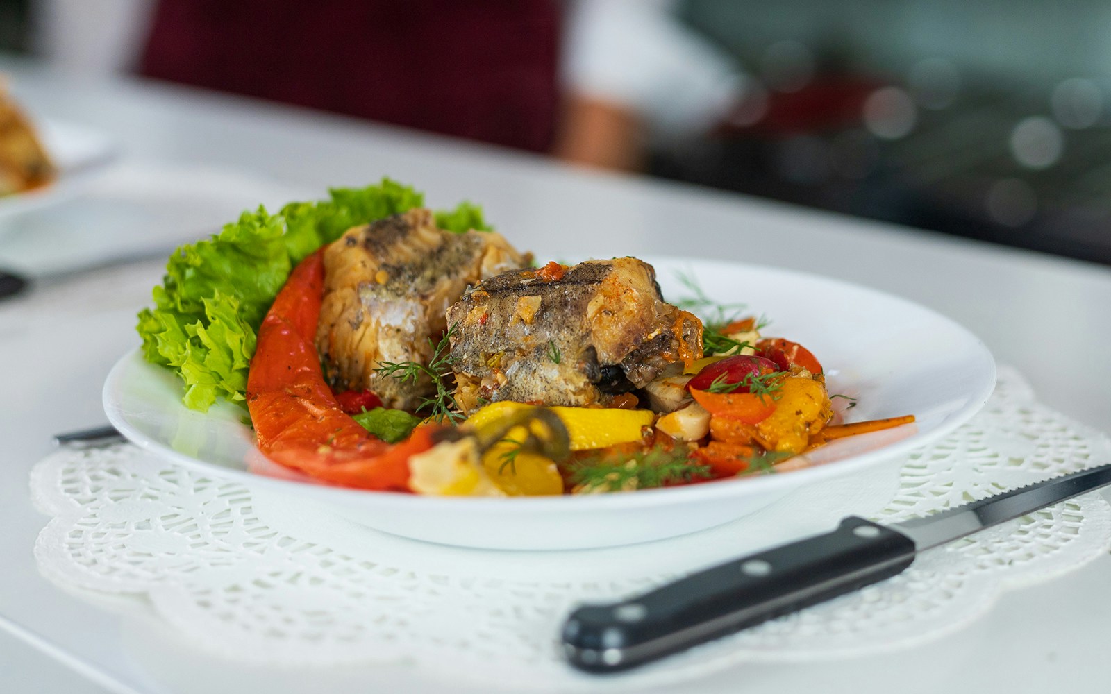 river fish dish with vegetables on a white plate.