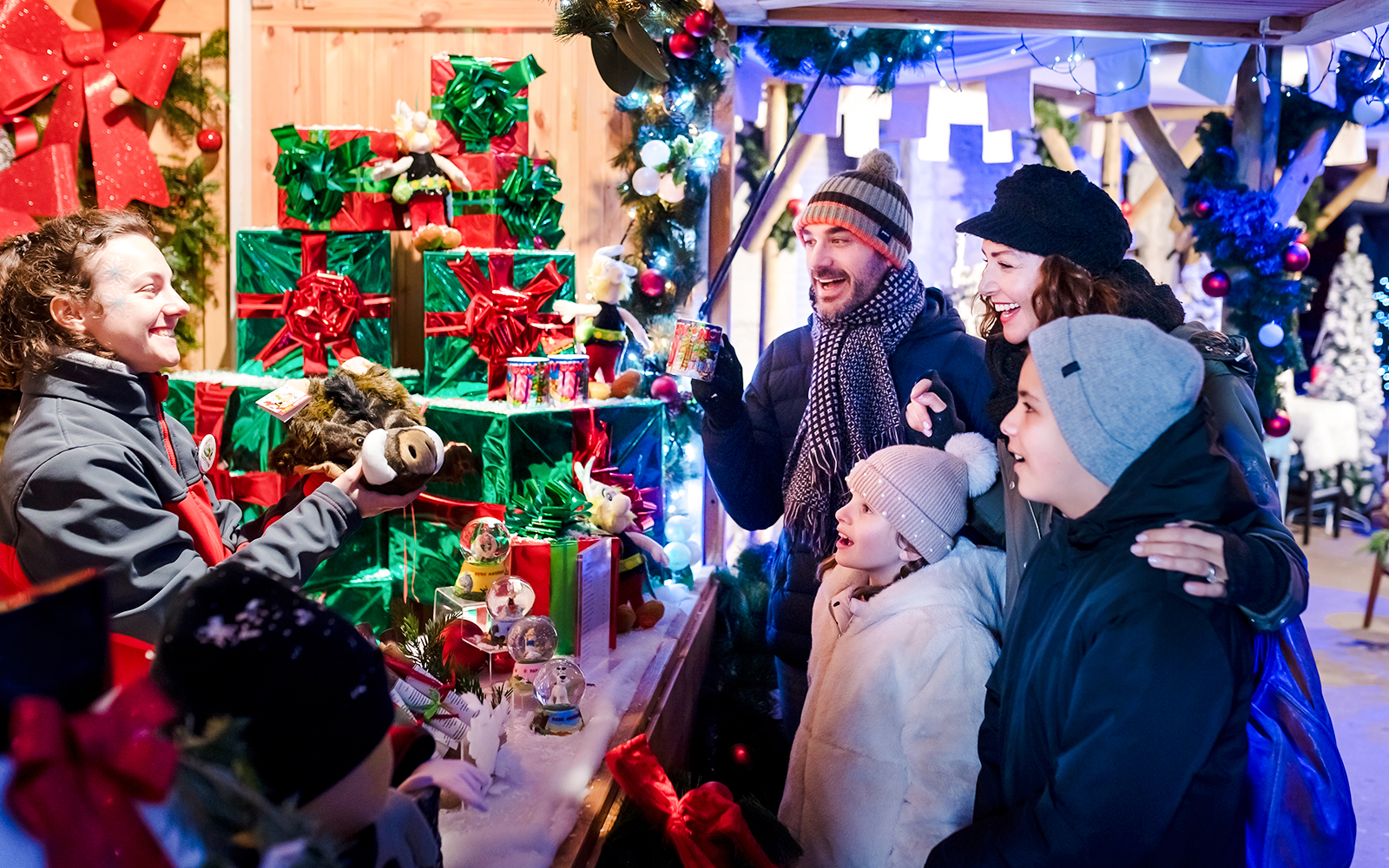 Family enjoying Christmas market at Parc Asterix with festive decorations and gifts.