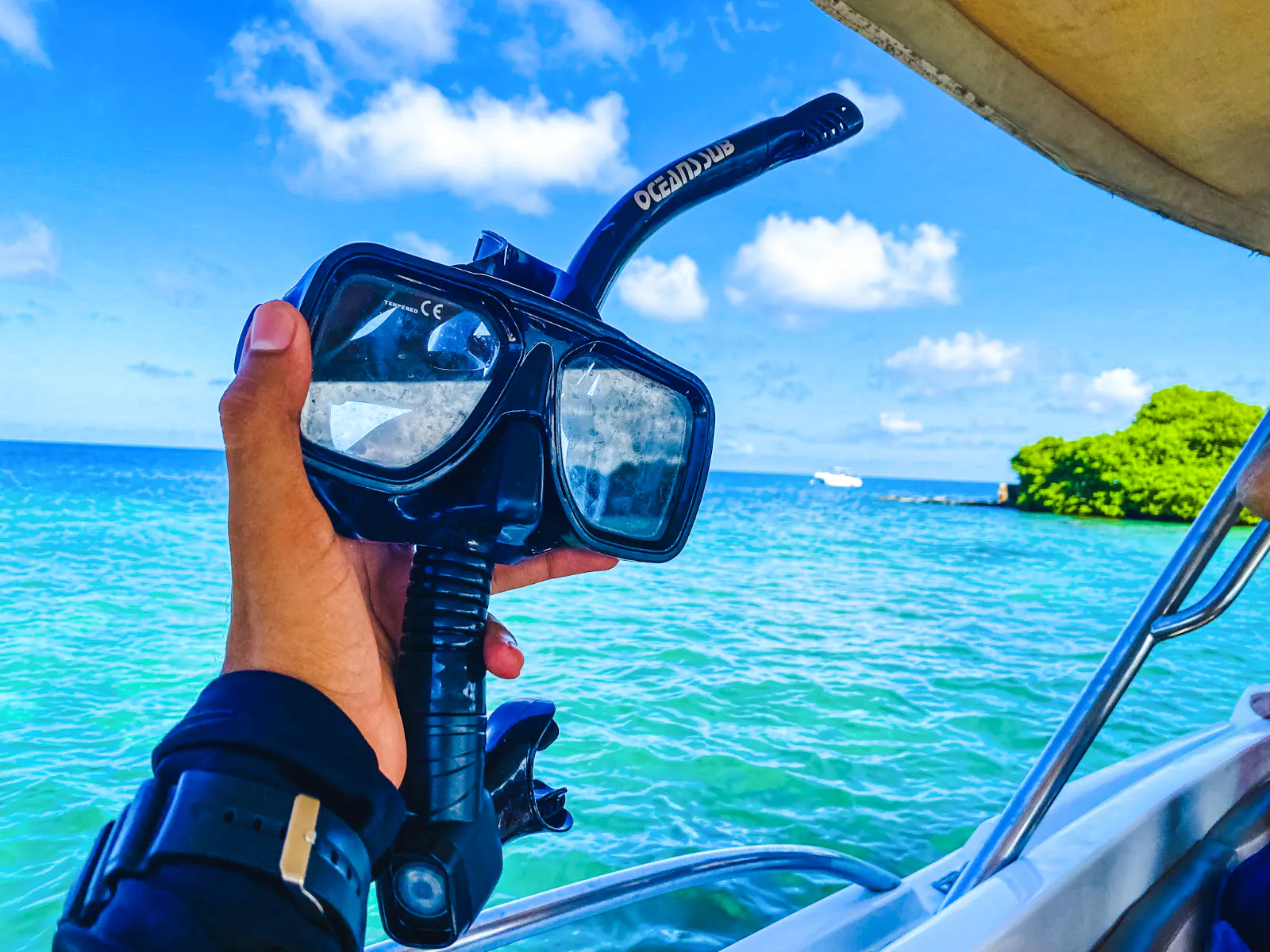 Snorkeling gear held on a boat with view of Rosario Islands' clear waters, Cartagena.