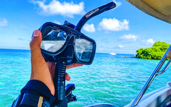 Snorkeling gear held on a boat with view of Rosario Islands' clear waters, Cartagena.