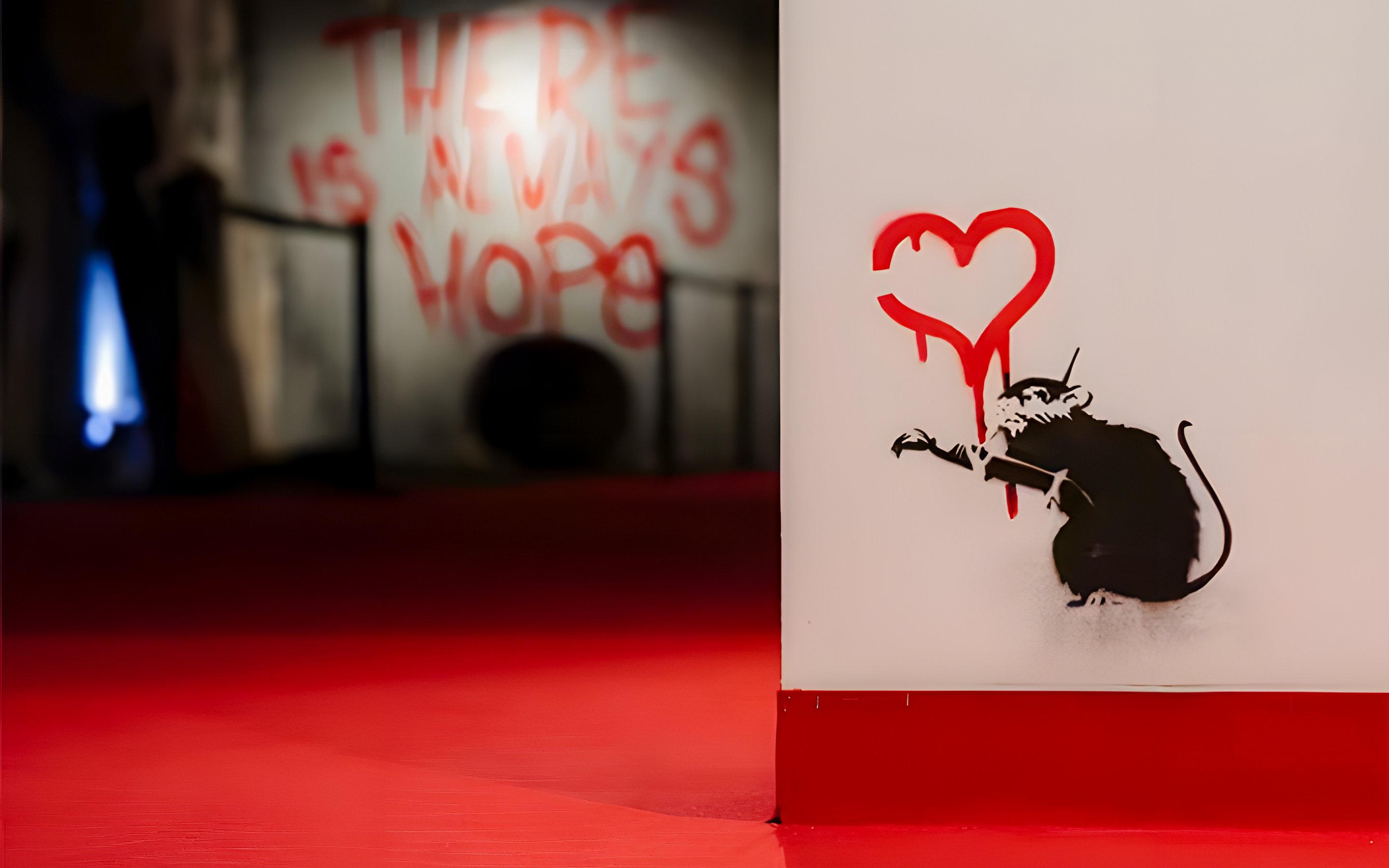 Graffiti of a rat with a red heart at Banksy Limitless Exhibition.