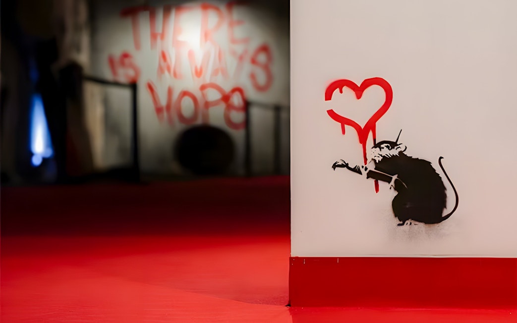 Graffiti of a rat with a red heart at Banksy Limitless Exhibition.