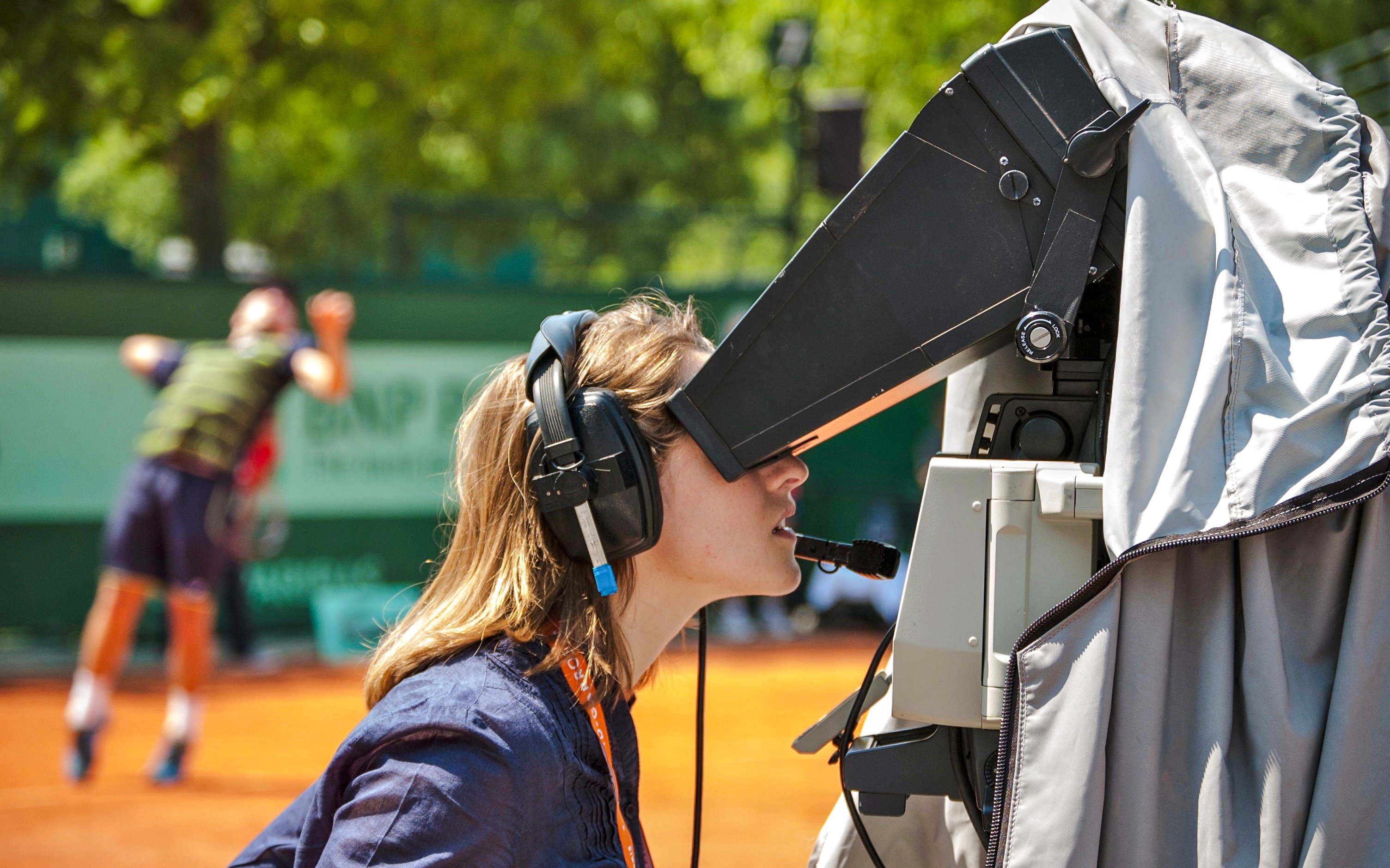 Camera operator filming a tennis match at Roland-Garros Stadium.