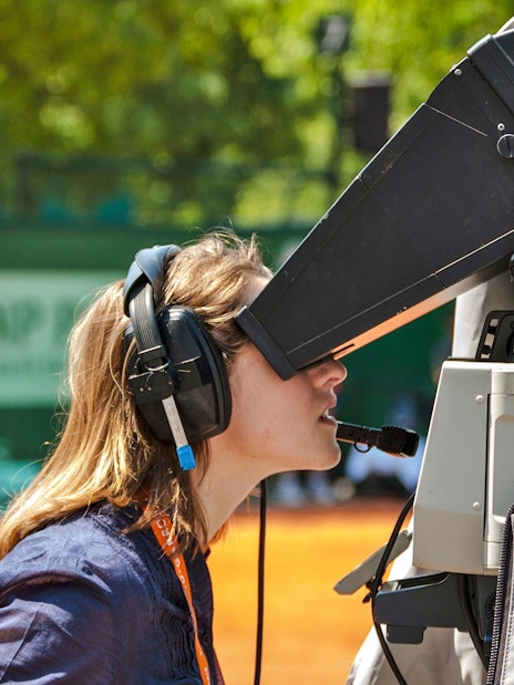 Camera operator filming a tennis match at Roland-Garros Stadium.