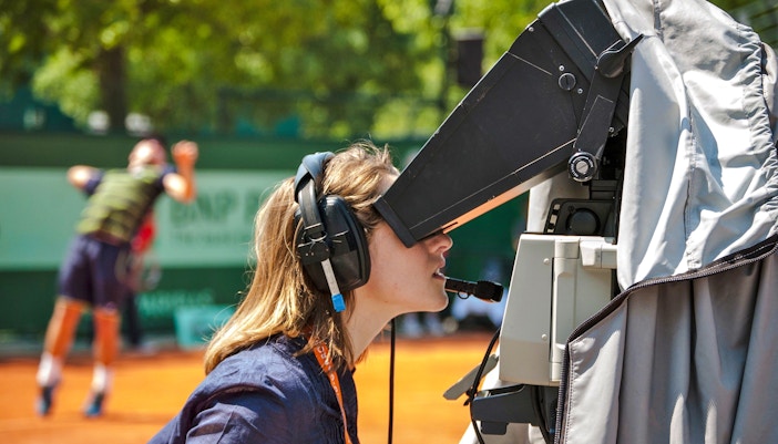 Camera operator filming a tennis match at Roland-Garros Stadium.