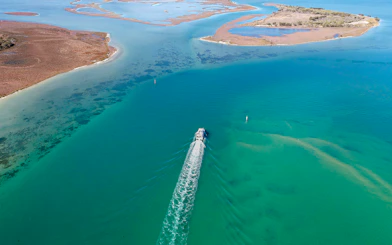 Aerial view of a cruise ship sailing through turquoise waters near coastal islands.