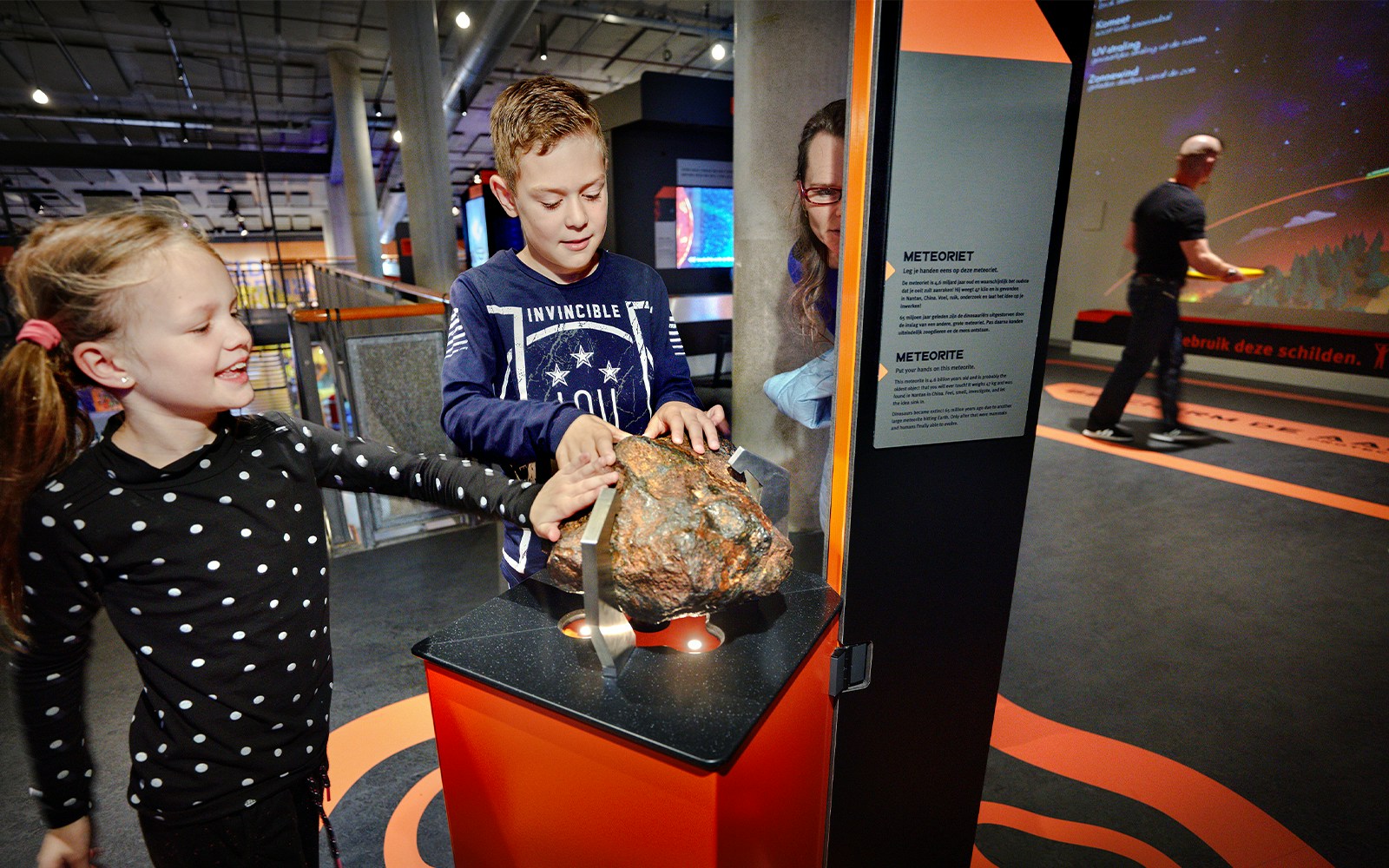 Children exploring a meteorite exhibit at NEMO Science Museum, Amsterdam.