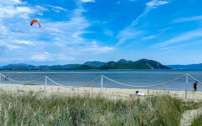 Kiteboarding on the beach at Delta Neretva, Croatia with mountains in the background.