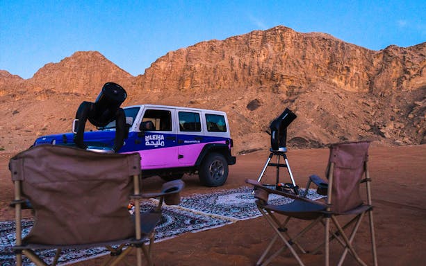 Telescopes and chairs set up for stargazing at Mleiha Space Camp with desert backdrop.
