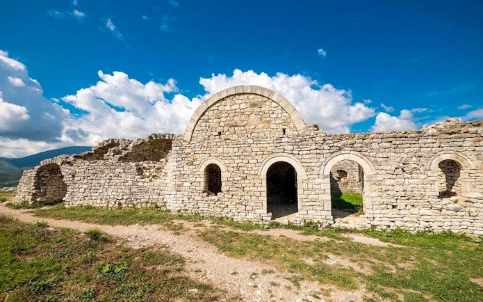 Berat Castle stone ruins under a blue sky in Albania.