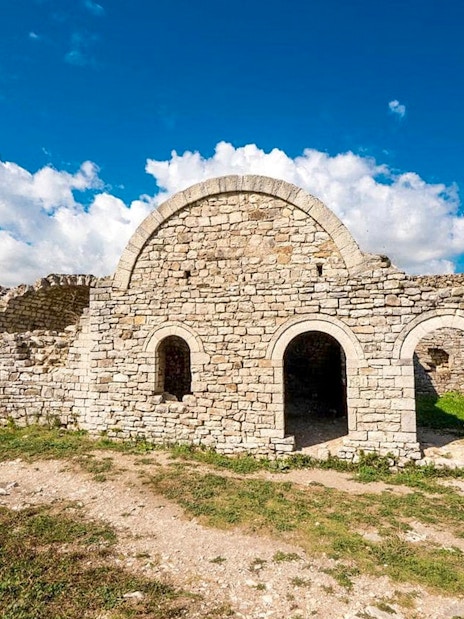 Berat Castle stone ruins under a blue sky in Albania.