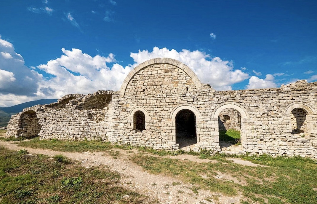 Berat Castle stone ruins under a blue sky in Albania.