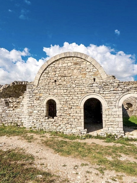 Berat Castle stone ruins under a blue sky in Albania.