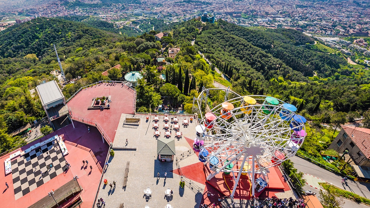 Aerial view of Tibidabo Amusement Park with Ferris wheel and cityscape in Barcelona.