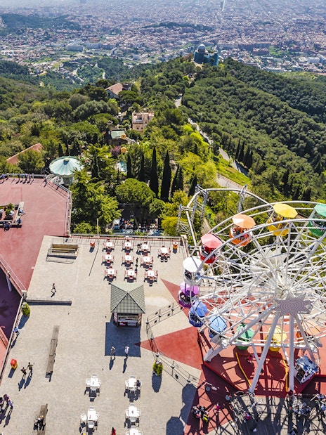 Aerial view of Tibidabo Amusement Park with Ferris wheel and cityscape in Barcelona.