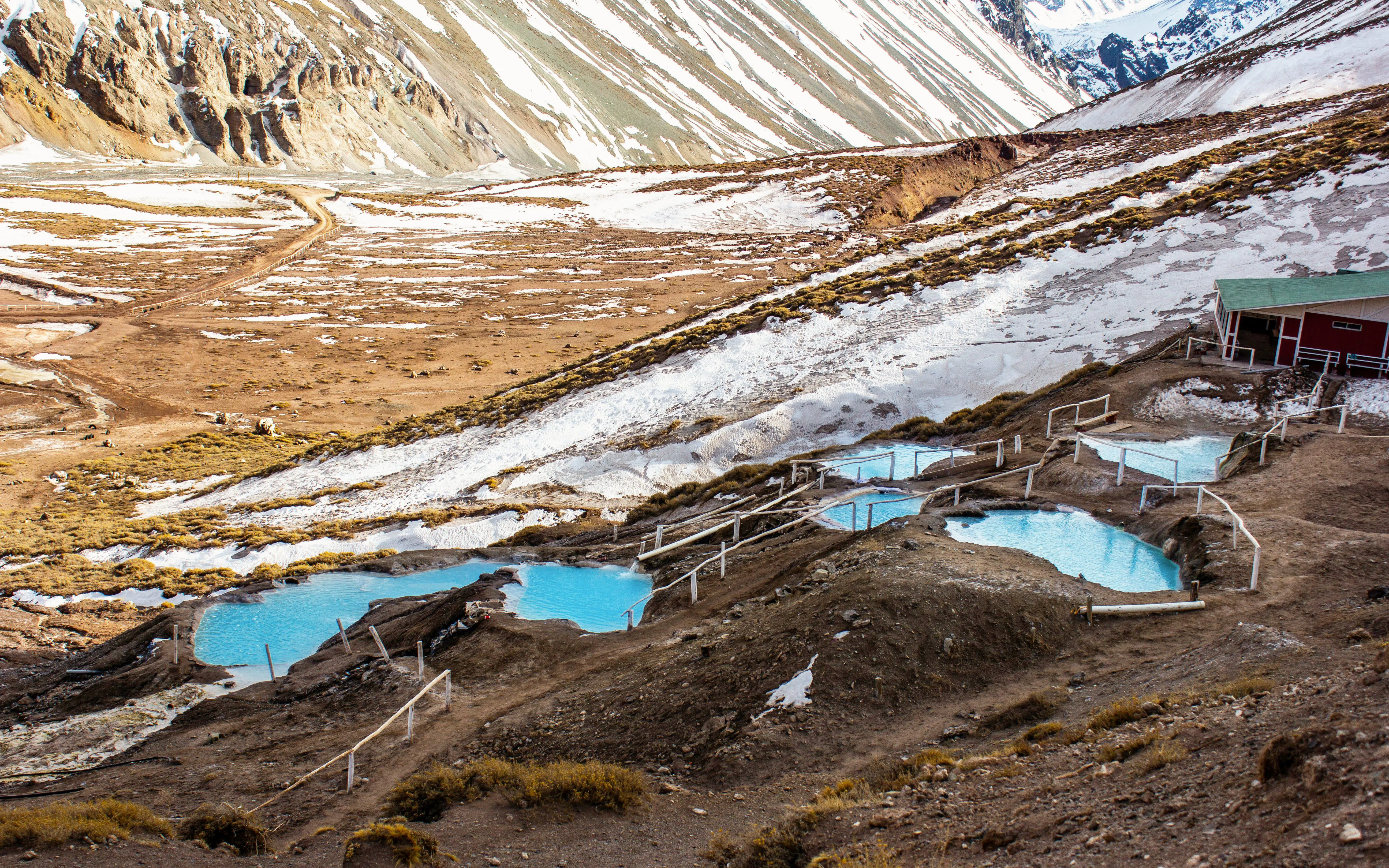 Termas Colina hot springs in Chile with snow-capped mountains in the background.