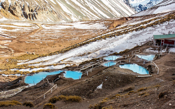Termas Colina hot springs in Chile with snow-capped mountains in the background.