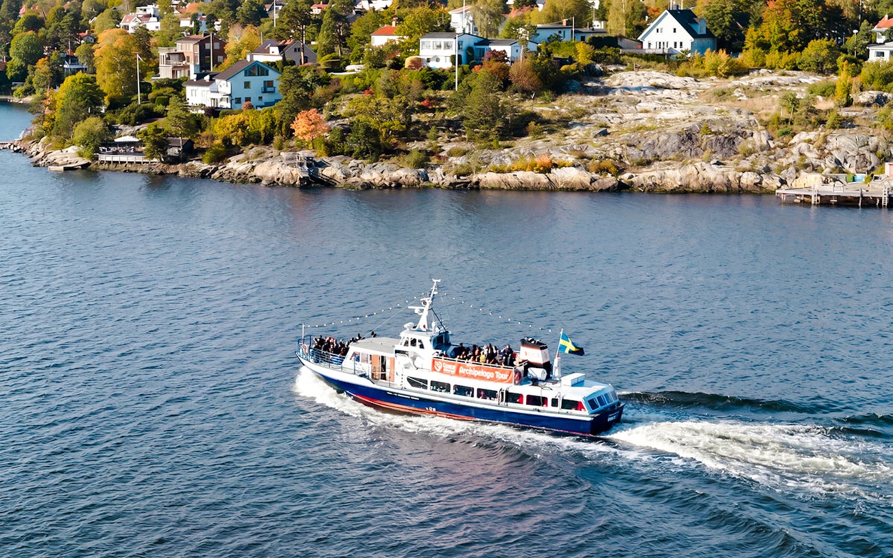 Boat cruising through Stockholm Archipelago with scenic coastal homes in view.