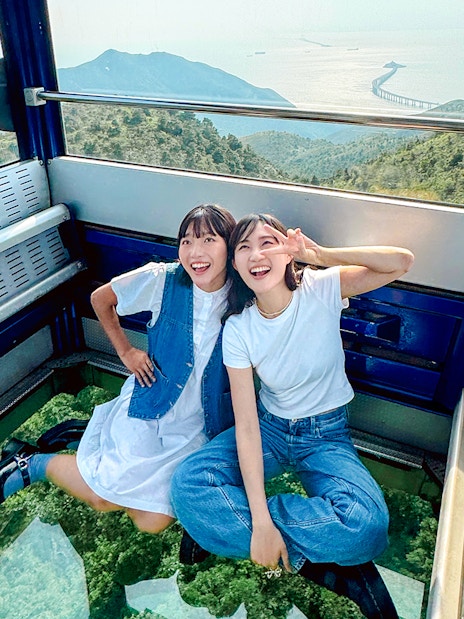 Tourists enjoying a cable car ride on Lantau Island with scenic views.