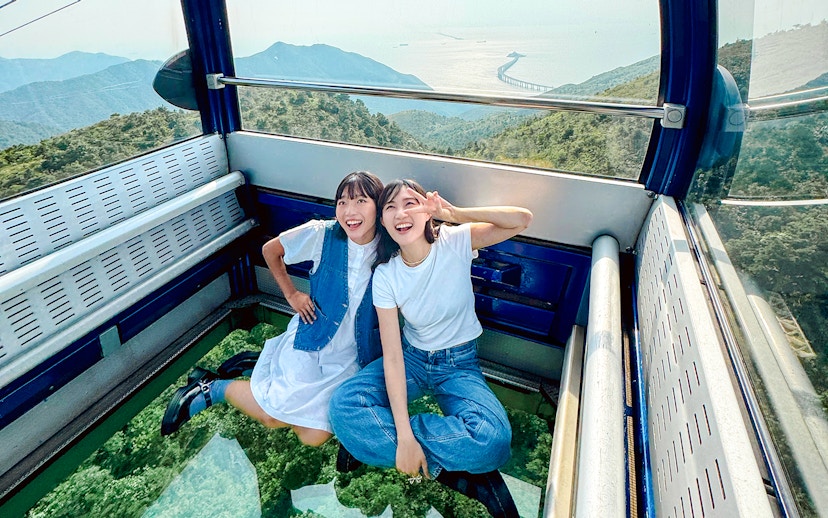 Tourists enjoying a cable car ride on Lantau Island with scenic views.