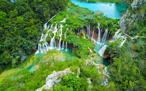Aerial view of cascading waterfalls and lush greenery at Plitvice Lakes during a tour from Split.