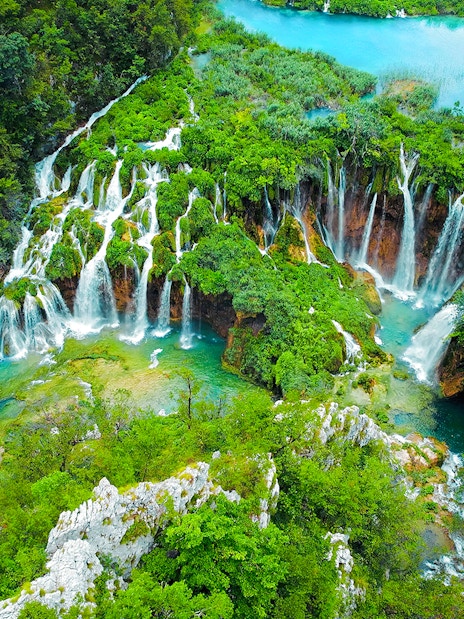 Aerial view of cascading waterfalls and lush greenery at Plitvice Lakes during a tour from Split.