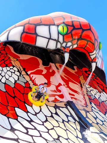 Group enjoying a yellow water slide at a theme park in Doha.