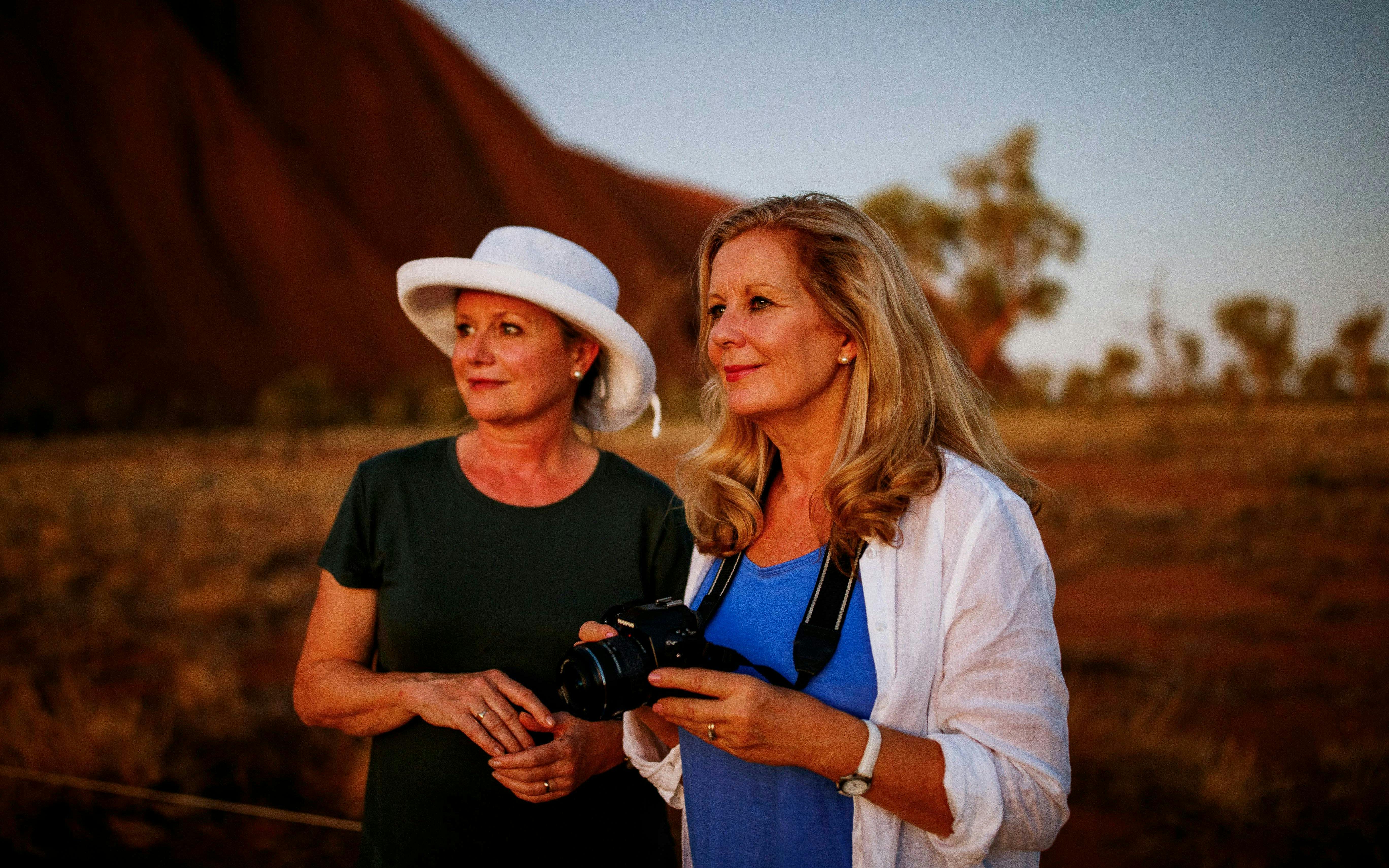 Two women enjoying a sunrise view at Uluru during a guided walking tour.