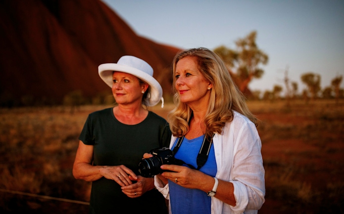 Two women enjoying a sunrise view at Uluru during a guided walking tour.