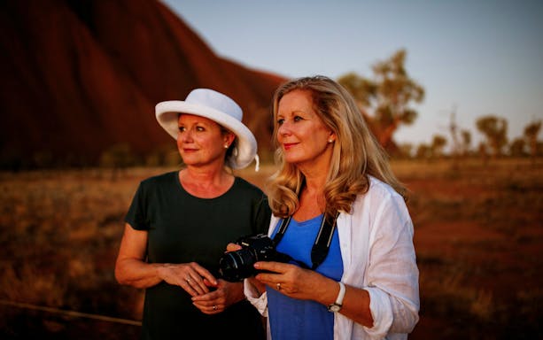 Two women enjoying a sunrise view at Uluru during a guided walking tour.