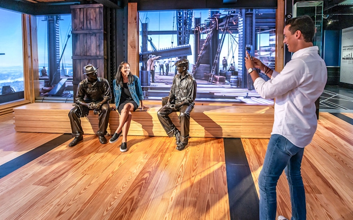 Man photographing woman with bronze statues on 86th floor, VIP Sunrise Experience.