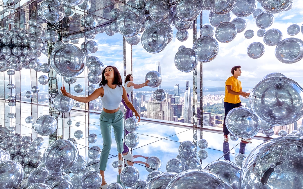Visitors exploring mirrored room with reflective spheres at SUMMIT One Vanderbilt, New York City.