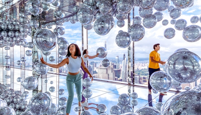 Visitors exploring mirrored room with reflective spheres at SUMMIT One Vanderbilt, New York City.