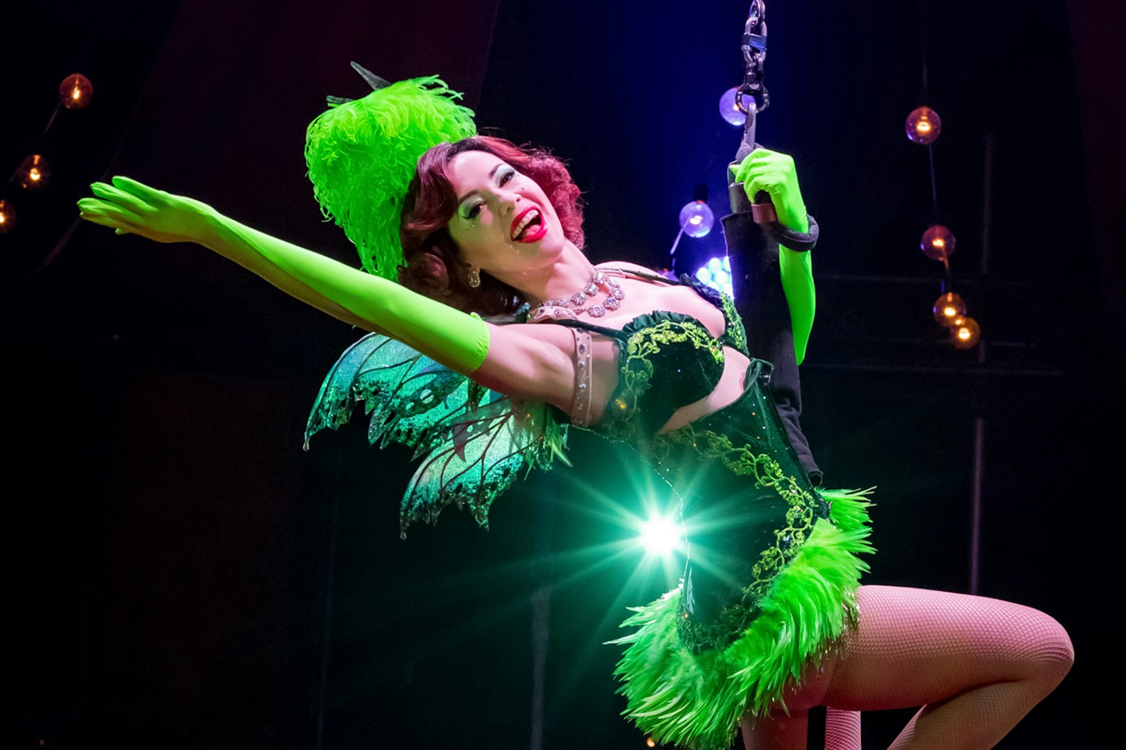 Performer in green costume on stage during Absinthe show.