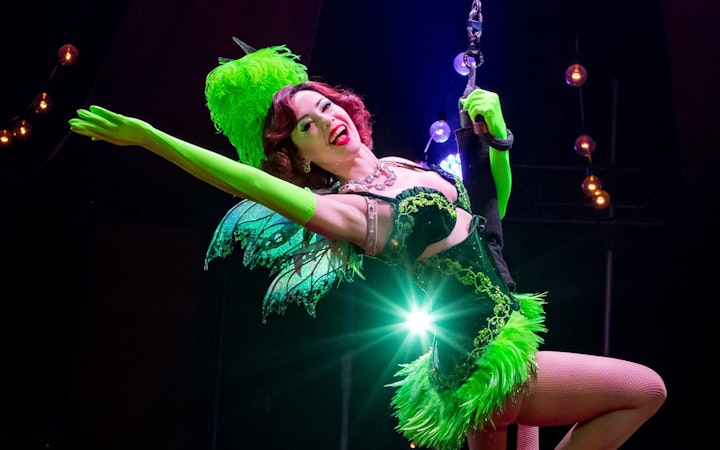 Performer in green costume on stage during Absinthe show.