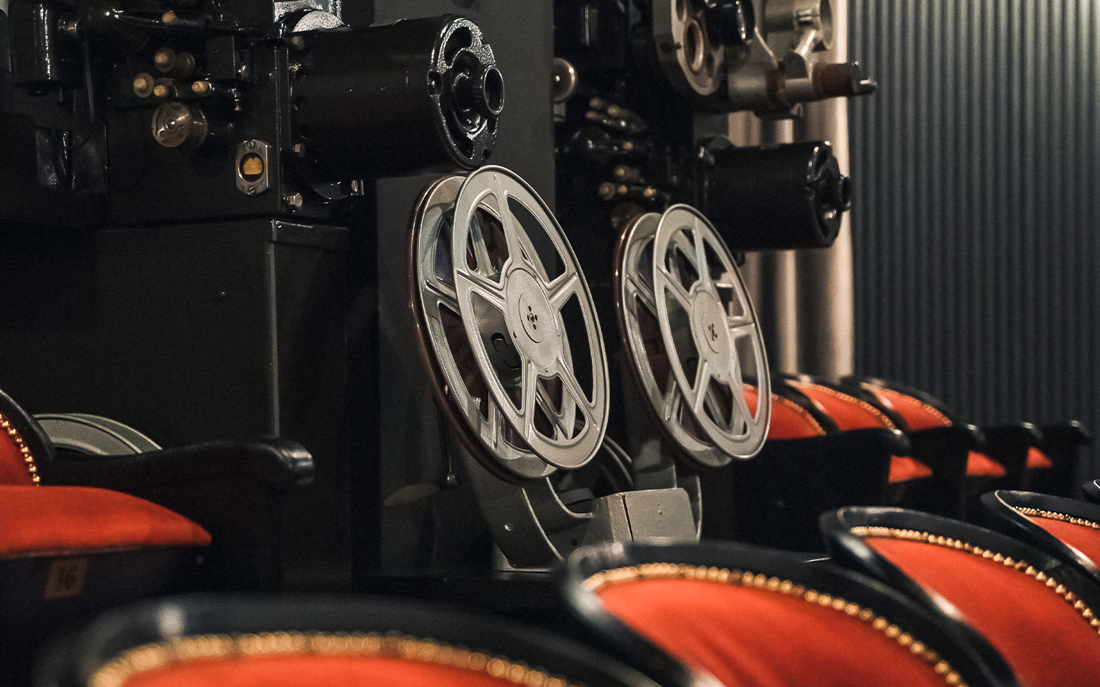Vintage film projector and red theater seats at Krakow Vodka Factory Museum.