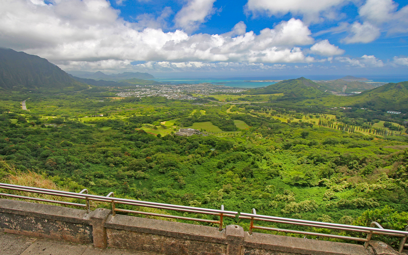 Windward coast of Oahu view from Nuuanu Pali Lookout, showcasing lush green landscape and ocean.