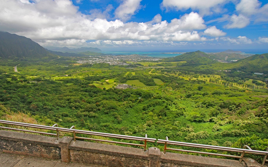 Windward coast of Oahu view from Nuuanu Pali Lookout, showcasing lush green landscape and ocean.