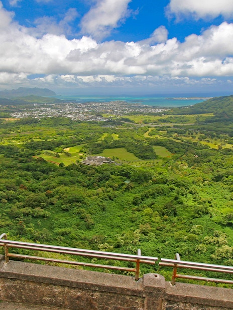 Windward coast of Oahu view from Nuuanu Pali Lookout, showcasing lush green landscape and ocean.