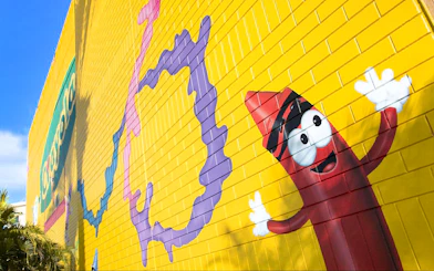 Colorful mural with Crayola crayon character on yellow wall at Crayola Experience, Orlando.