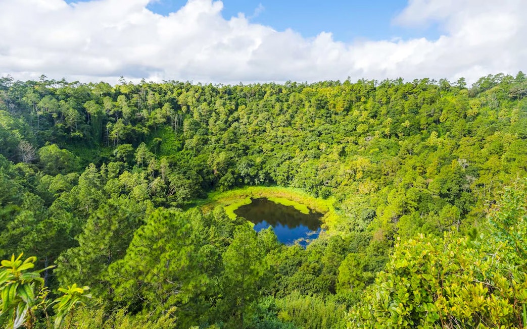 Trou aux Cerfs crater surrounded by lush greenery in Curepipe, Mauritius.