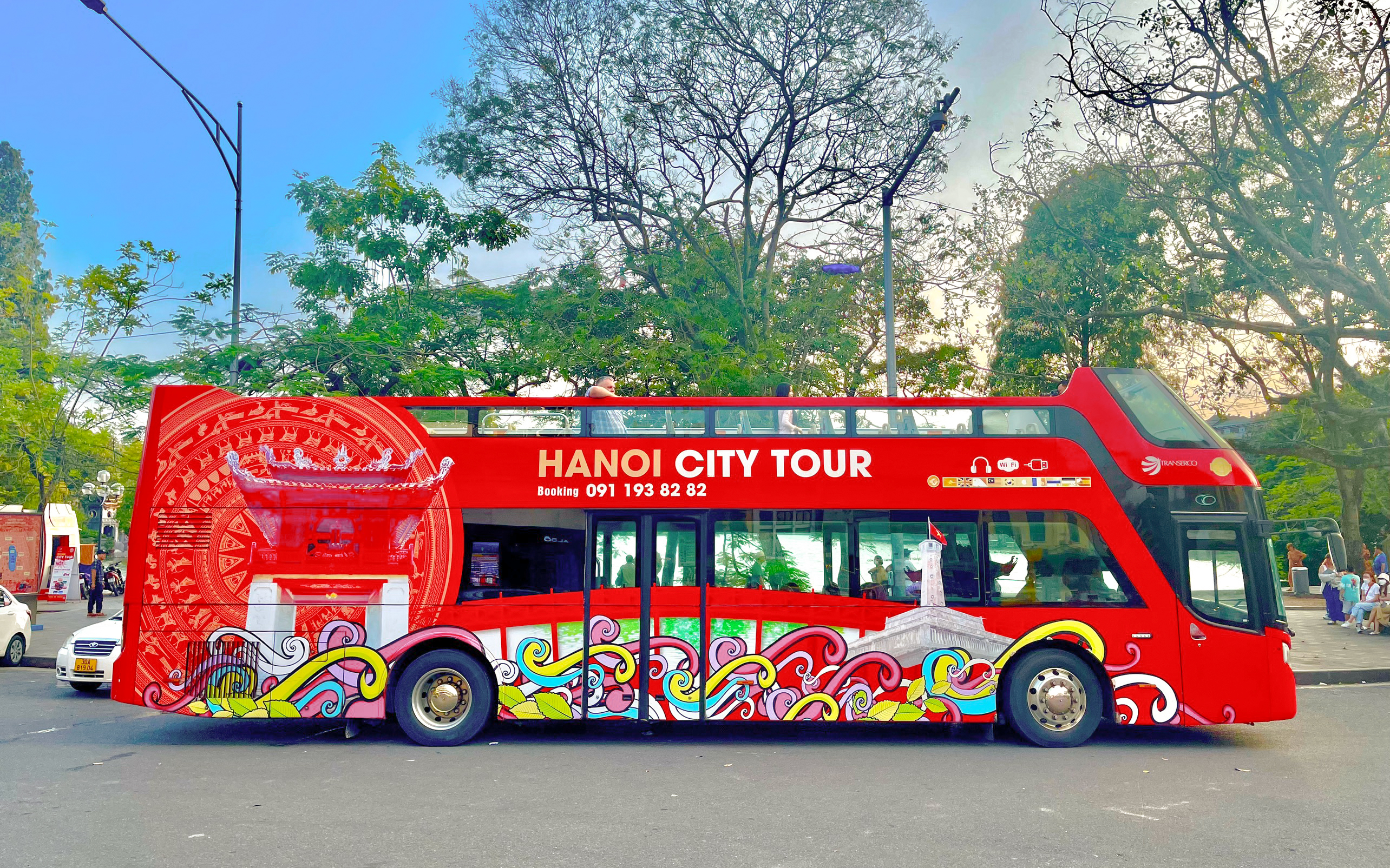 Hop on hop off tour bus in Hanoi, Vietnam with vibrant cityscape design.