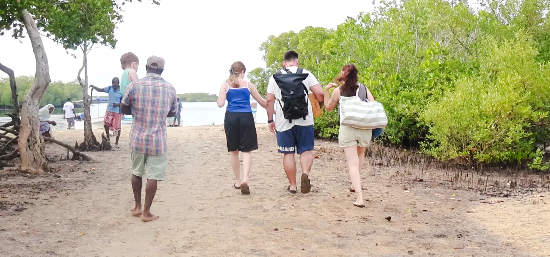 Group walking along a sandy path on Funzi Island, surrounded by lush greenery, during a Diani Beach excursion.