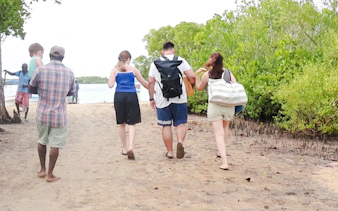 Group walking along a sandy path on Funzi Island, surrounded by lush greenery, during a Diani Beach excursion.