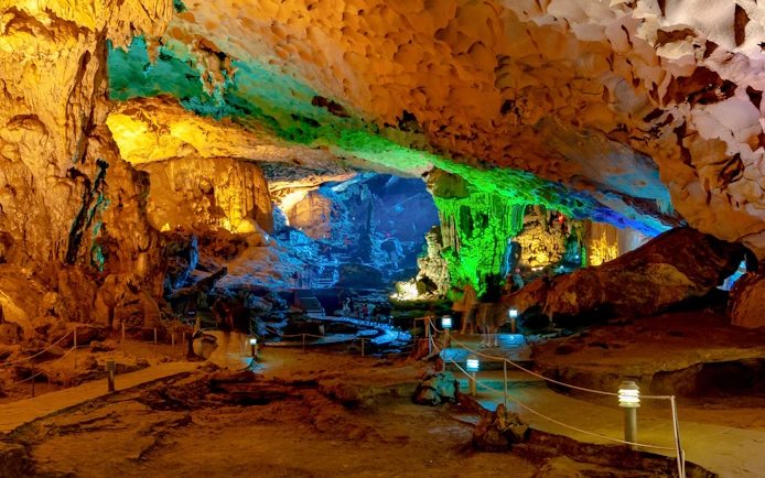 Sung Sot Cave interior with illuminated stalactites and colorful rock formations.
