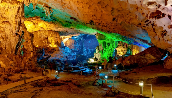 Sung Sot Cave interior with illuminated stalactites and colorful rock formations.