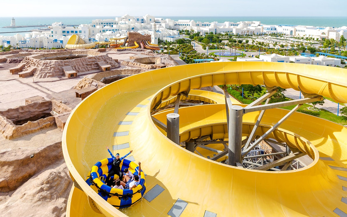 Group enjoying a yellow water slide at a theme park in Doha.